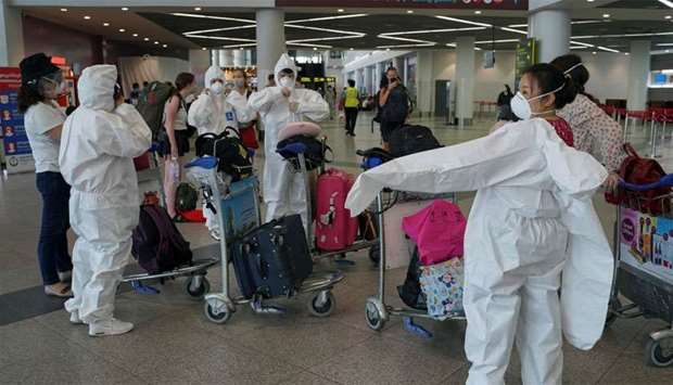 A group of travelers wear full protective suits and masks at Phnom Penh International Airport in Cambodia