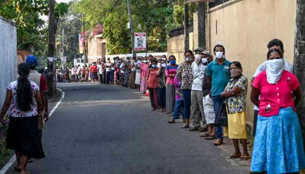 People wearing facemasks queue outside a shop at Piliyandala on the outskirts of Colombo yesterday, as the authorities briefly lifted a curfew.