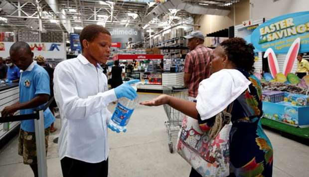A store assistant sprays hand sanitiser on people as shoppers stock up on groceries at a Makro Store ahead of a nationwide 21-day lockdown in an attempt to contain the  coronavirus disease (Covid-19) outbreak in Durban, yesterday.