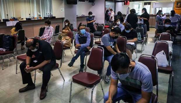 People sit apart from each other to maintain social distancing at an immigration office in Bangkok