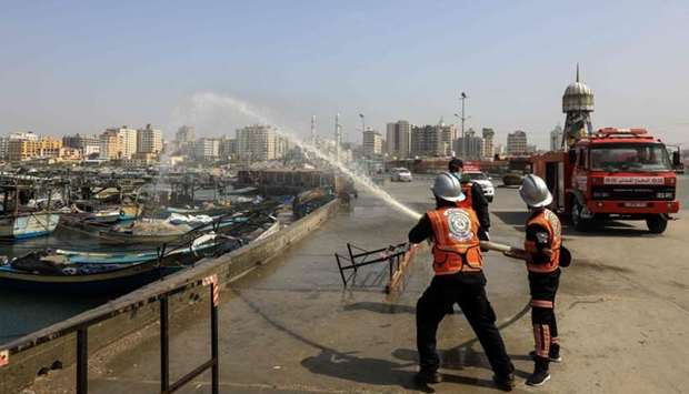 Members of the Palestinian civil defense force spray disinfectant in the port area in Gaza City, during a campaign by the Hamas to contain the novel coronavirus outbreak