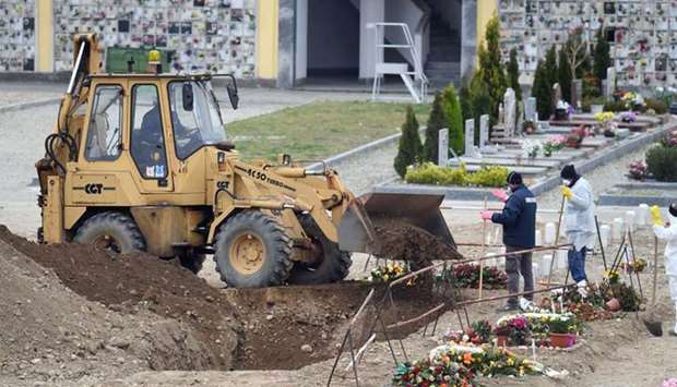 Workers use an excavator at a cemetery in Milan, as the spread of the coronavirus disease (Covid-19) continues.