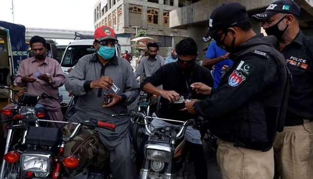 Officers check the identity cards of commuters before letting them cross a checkpoint in Karachi.