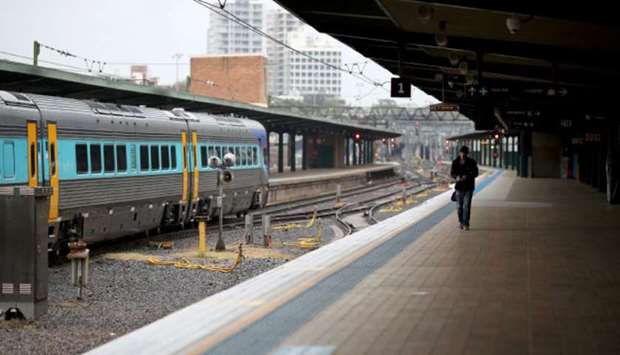 A man walks alone on a train platform at Central Station, as New South Wales begins shutting down non-essential businesses and moving toward harsh penalties to enforce self-isolation in Sydney, Australia, yesterday.