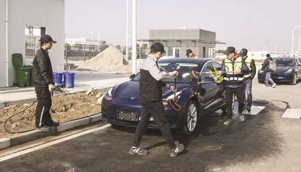 Workers clean a Tesla Model 3 vehicle at the companyu2019s Gigafactory in Shanghai. After resuming operations on February 10, the plant u2013 Teslau2019s only outside the US u2013 has surpassed the capacity it had before the shutdown, reaching a weekly production of 3,000 cars, a company representative said.