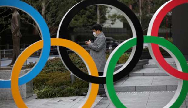 In this March 4, 2020, picture, a man looks at his mobile phone next to The Olympic rings in front of the Japan Olympics Museum in Tokyo. (Reuters)