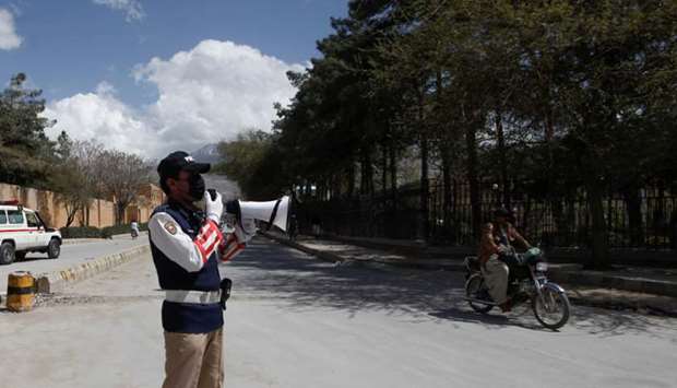A police officer uses a megaphone to alert people in Quetta amid an outbreak of the coronavirus.
