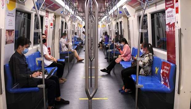 Passengers wearing protective face masks due to coronavirus disease (COVID-19) outbreak, sit on social distancing seats as they travel on a train in Bangkok, Thailand