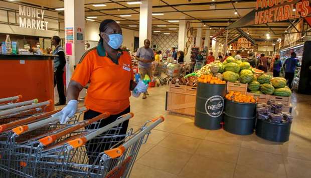 A worker disinfects shopping trolleys as customers shop in the Naivas Supermarket in Nairobi, Kenya.