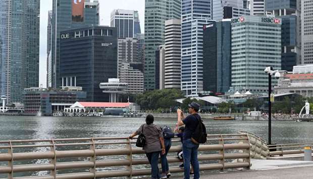 A man takes a photo as the financial business district looms in the background in Singapore. One of the worldu2019s most open economies which is viewed as a barometer for the health of global trade, Singapore is now heading for a deep recession this year after shrinking 2.2% on-year in January-March.