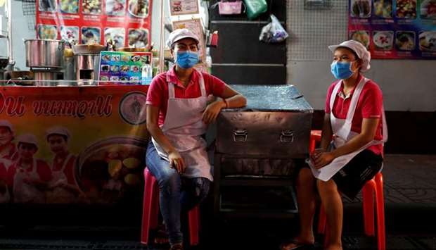 Women wearing masks wait for customers at a food stall during the coronavirus disease outbreak, in Chinatown, one of the city's top tourist spots, in Bangkok, Thailand