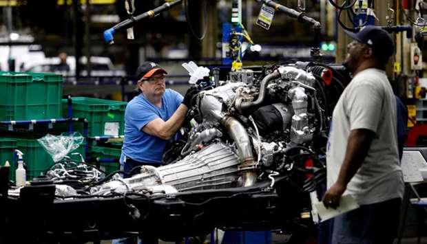 In this file photo taken on June 12, 2019 line workers work on the chassis of full-size General Motors pickup trucks at the Flint Assembly plant in Flint, Michigan