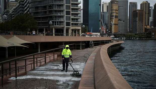 A worker cleans the mostly deserted waterfront area of the Sydney Opera House