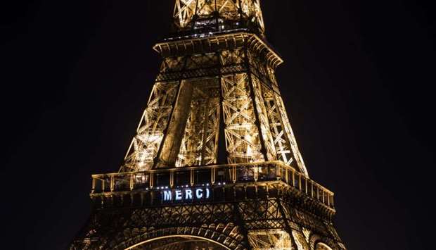This picture shows the word ,merci, (thank you in French ) displayed in tribute to healthcare workers on the Eiffel Tower in Paris Friday, on the 11th day of a lockdown in France aimed at curbing the spread of Covid-19.