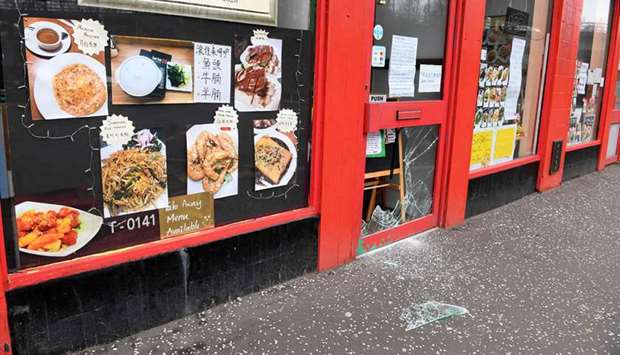 Glass is strewn on the pavement in front of the vandalised door of a Chinese restaurant in Glasgow, Scotland, yesterday. Britain is under lockdown due to the spread of the coronavirus.