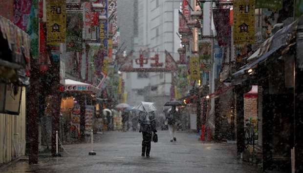 A man walks past on a nearly empty street in a snow fall during the first weekend after Tokyo Governor Yuriko Koike urged Tokyo residents to stay indoors in a bid to keep the coronavirus disease (Covid-19) from spreading, at Ameyoko shopping and amusement district in Tokyo