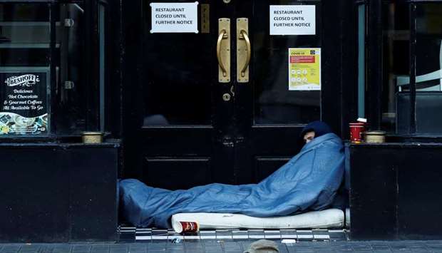 A homeless person is seen lying at the entrance of a restaurant in Dublin, Ireland, yesterday as the spread of the coronavirus disease continues.
