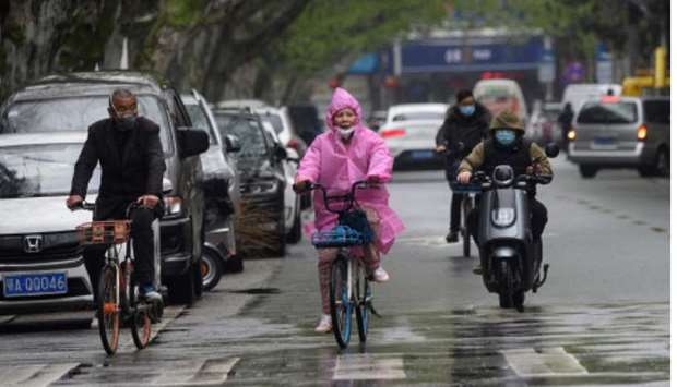 People wearing face masks ride along a street in Wuhan, in Chinau2019s central Hubei province yesterday.