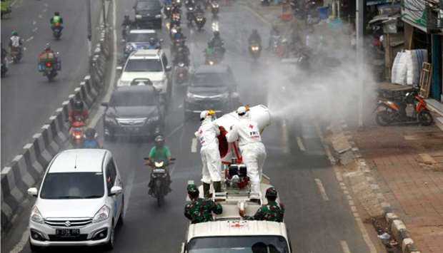 Red Cross personnel wearing protective suits spray disinfectant on the road to prevent the spread of the coronavirus disease (Covid -19) in Jakarta yesterday.