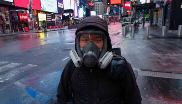 A man wears a face mask while he visits Times Square as rain falls in New York City on Saturday.