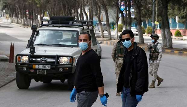 People wear face masks at a check point in the northern governorate of Irbid, Jordan, as the city has been isolated and people were banned from entering it, after the number of Covid-19 cases increased in the area.