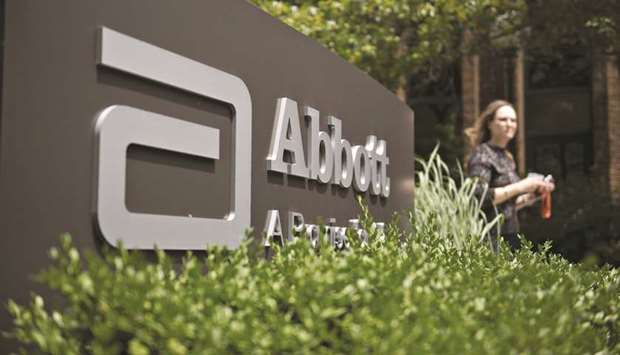 An employee walks near an Abbott Laboratories sign at the companyu2019s headquarters complex in Abbott Park, Illinois. The medical-device maker plans to supply 50,000 tests a day starting April 1, said John Frels, vice president of research and development at Abbott Diagnostics. These tests can tell if someone is infected in as little as five minutes.