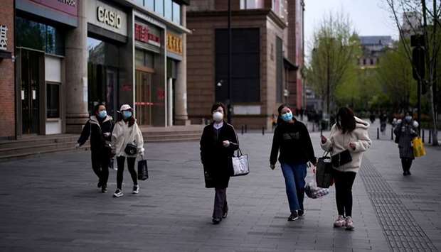 People wearing face masks walk at a shopping area in Wuhan, Hubei province, the epicentre of Chinau2019s coronavirus disease (Covid-19) outbreak yesterday.