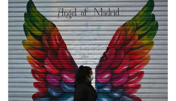 A woman walks past a closed shop in Madrid during a national lock-down to prevent the spread of the new coronavirus.