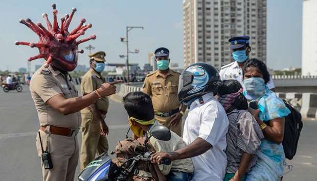 Police inspector Rajesh Babu wearing a coronavirus-themed helmet speaks to a family on a motorbike at a checkpoint during a government-imposed nationwide lockdown, in Chennai yesterday.