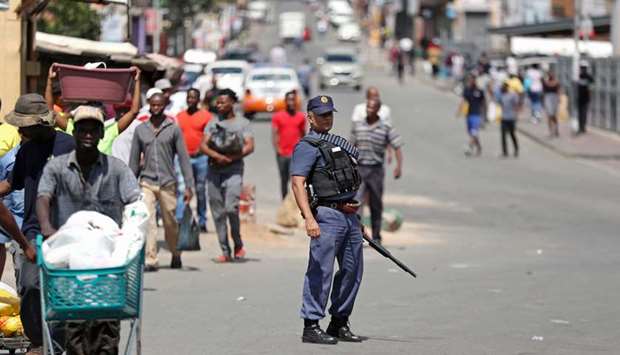 A police officer looks on as locals go on their daily business on the first day of a nationwide lockdown for 21 days to try to contain the coronavirus disease (Covid-19) outbreak, in Alexandra, South Africa, on March 27.