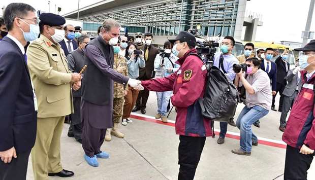 This photograph taken and released by Pakistanu2019s Press Information Department (PID) shows Foreign Minister Shah Mehmood Qureshi welcoming one of the Chinese doctors upon their arrival at Islamabadu2019s international airport.