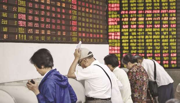 Investors stand at trading terminals in front of electronic stock boards at a securities brokerage in Shanghai. 