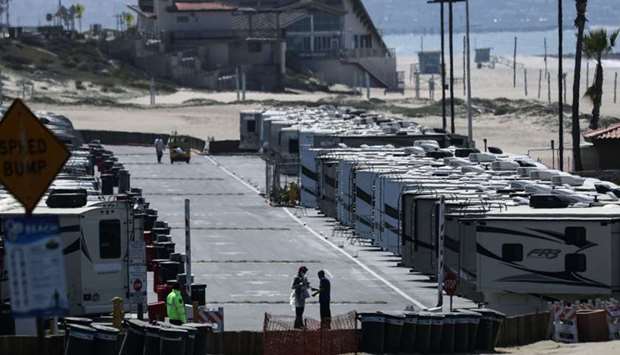 People stand near RV's at Dockweiler State Beach, in an area being used as an isolation zone for those who cannot self-isolate and are being asked to quarantine by the Los Angeles County Department of Health, amid the coronavirus pandemic on March 28, 2020 in Los Angeles, California
