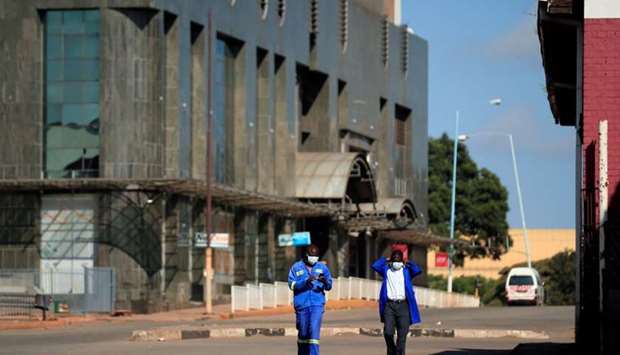 Men wear protective masks as they walk down a deserted street on the first day of the 21-day nationwide lockdown aimed at limiting the spread of coronavirus disease (Covid-19) in Harare, Zimbabwe. Reuters