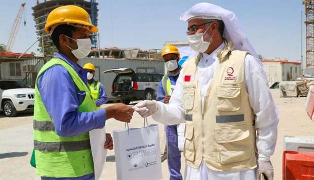 A Qatar Charity official handing over a kit to a worker.