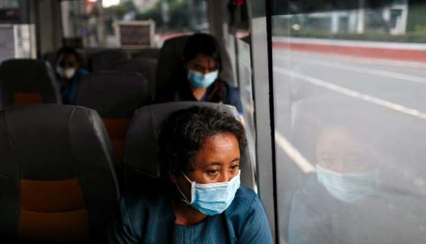 A medical worker wearing a protective mask rides a free shuttle service for healthcare workers following the suspension of mass transportation in Metro Manila to contain the spread of the coronavirus disease (Covid-19), in Manila, yesterday.