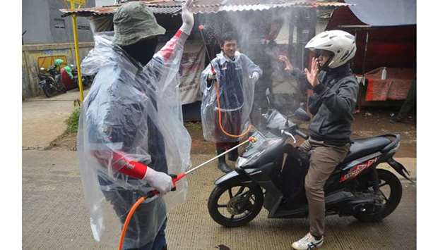 Indonesian men spray disinfectant on a motorist as he enters a neighbourhood amid Covid-19 coronavirus outbreak in Bekasi yesterday.