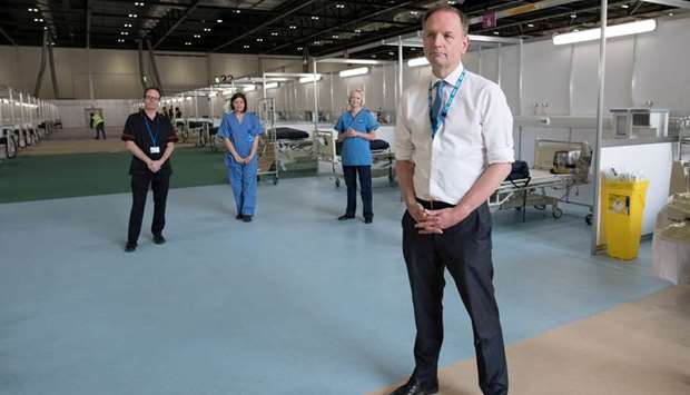NHS Englandu2019s chief executive Simon Stevens stands with NHS staff during a visit to the ExCel London in Newham, London, yesterday. The ExCel centre has been converted into the temporary NHS Nightingale Hospital, comprising two wards, each capable of accommodating 2,000 people.