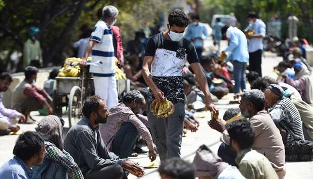 Homeless people sit in lines outside a shelter to get food in New Delhi yesterday.