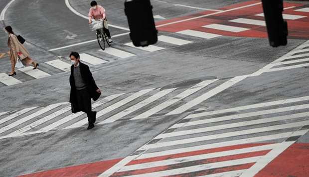 Pedestrians wearing protective face masks, following an outbreak of the coronavirus disease (COVID-19), walk on the crossing at Shibuya shopping and amusement district in Tokyo, Japan March 31, 2020.