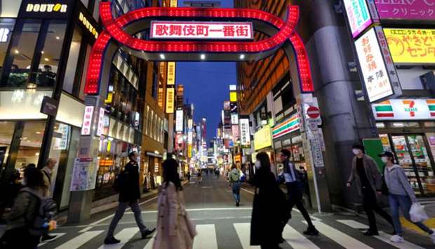 People cross a street at Tokyou2019s entertainment district Kabukicho.  Tokyo Governor Yuriko Koike urged residents to stay away from karaoke parlours, bars and nightclubs to prevent the coronavirus from spreading.