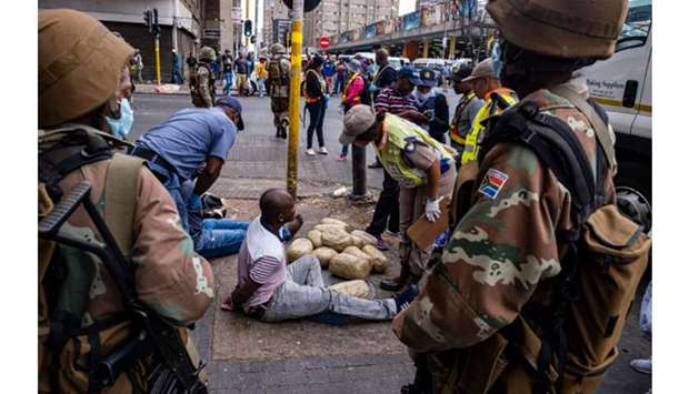 Soldiers of the South African National Defence Force looks on as law enforcement officers arrests two men after being caught with large amounts of drugs during an operation in Johannesburg yesterday.