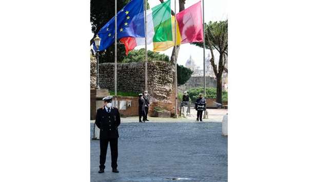 Municipal police officers stand at attention beside the flags of (from left) Europe, Italy and Rome, flying at half-mast during a minute of silence outside Romeu2019s city hall at Capitoline Hill (Campidoglio).