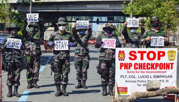 Police personnel hold up placards reminding people to stay at home amid concerns of the spread of the Covid-19 coronavirus in Manila, yesterday.