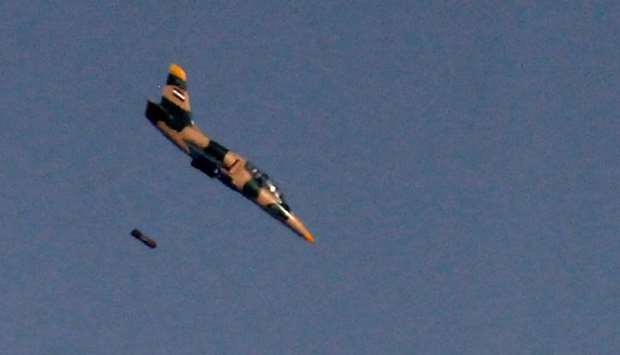 This file photo taken on July 25, 2018 from the Tal Saki hill in the Israeli-annexed Golan Heights shows a Syrian Aero L-39 Albatros war plane dropping a payload above buildings across the border in Syria during air strikes backing a Syrian-government-led offensive in the southern province of Quneitra