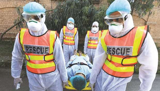 Rescue workers wearing masks and protective clothing move a man during a drill in Peshawar on handling suspected carriers of coronavirus.