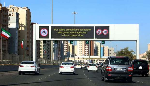 Vehicles pass by a billboard showing precautionary instructions against the COVID-19 coronavirus disease as they drive along a main highway in Kuwait City