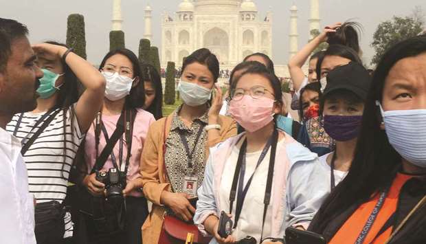 Tourists wearing protective masks are pictured at the historic Taj Mahal in Agra yesterday.