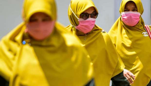 Women wearing face masks walk in a public area in Banda Aceh on March 2