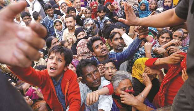 People crowd to receive free grocery items being distributed outside a relief camp after they fled their homes following Hindu-Muslim clashes triggered by a new citizenship law, in Mustafabad in the riot-affected northeast of New Delhi yesterday.
